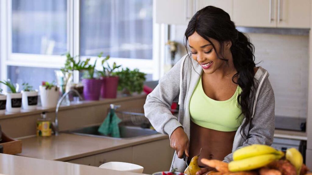 A smiling woman preparing a healthy meal in a bright kitchen, representing the importance of balanced nutrition and sustainable lifestyle choices.